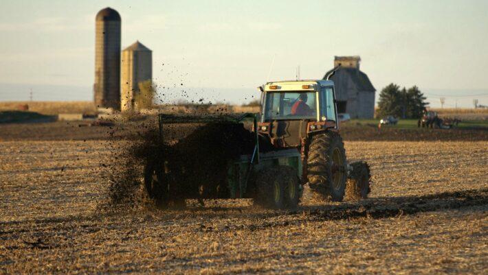 tractor spreading sewage sludge on farm field